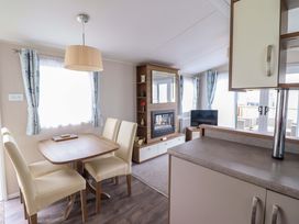 A living room with a dining table and television at Sea Breeze C38 Dyffryn Seaside Estate Dyffryn Ardudwy