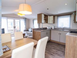 A kitchen and dining area with table and chairs at Sea Breeze C38 Dyffryn Seaside Estate Dyffryn Ardudwy