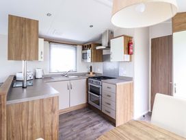 A kitchen with cabinets and appliances at Sea Breeze C38 Dyffryn Seaside Estate Dyffryn Ardudwy