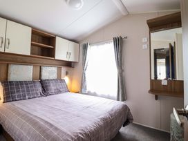 A bedroom with a bed and window at Sea Breeze C38 Dyffryn Seaside Estate Dyffryn Ardudwy