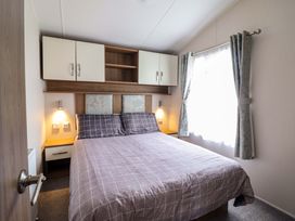 A bedroom with a bed and wardrobe at Sea Breeze C38 Dyffryn Seaside Estate Dyffryn Ardudwy