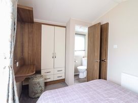 A bedroom with a bed and attached bathroom at Sea Breeze C38 Dyffryn Seaside Estate Dyffryn Ardudwy
