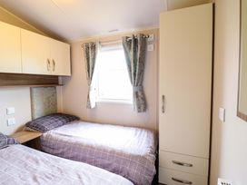 A bedroom with two beds and a wardrobe at Sea Breeze C38 Dyffryn Seaside Estate Dyffryn Ardudwy