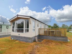 A mobile home with a deck and garden at Beach Retreat E19 Dyffryn Seaside Estate Dyffryn Ardudwy