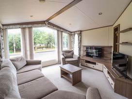 A living room with a sofa and a television at Beach Retreat E19 Dyffryn Seaside Estate Dyffryn Ardudwy