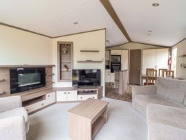 A living room with a sofa, coffee table, and television at Beach Retreat E19 Dyffryn Seaside Estate, Dyffryn Ardudwy