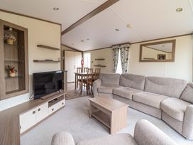 A living room with a sofa and dining table at Beach Retreat E19 Dyffryn Seaside Estate Dyffryn Ardudwy