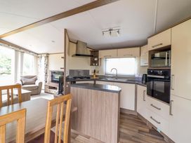 A kitchen and dining area with a table and chairs at Beach Retreat E19 Dyffryn Seaside Estate in Dyffryn Ardudwy