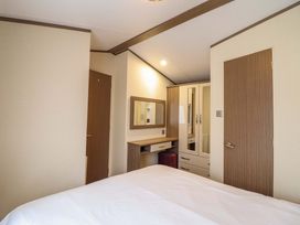 A bedroom with a bed and wardrobe at Beach Retreat E19 Dyffryn Seaside Estate Dyffryn Ardudwy