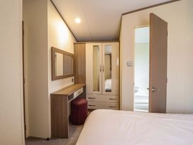 A bedroom with a bed, wardrobe, and mirror at Beach Retreat E19 Dyffryn Seaside Estate Dyffryn Ardudwy