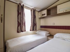 A bedroom with two beds and curtains at Beach Retreat E19 Dyffryn Seaside Estate Dyffryn Ardudwy