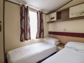 A bedroom with two single beds and curtains at Beach Retreat E19 Dyffryn Seaside Estate Dyffryn Ardudwy