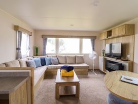 A living room with a sofa, table and television at Beachcombers Barmouth Bay Holiday Park Talybont
