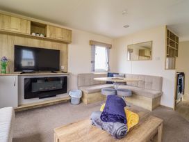 A living room with a television and dining table at Beachcombers Barmouth Bay Holiday Park Talybont