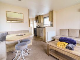 A living room with a sofa, table, and kitchen amenities at Beachcombers Barmouth Bay Holiday Park Talybont