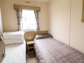 A bedroom with a bed and a nightstand at Beachcombers Barmouth Bay Holiday Park in Talybont