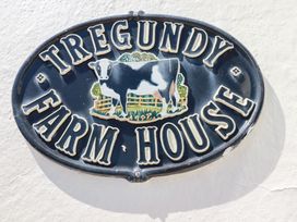 A sign featuring Tregundy Farmhouse with a cow illustration at Tregundy Farmhouse in Perranporth