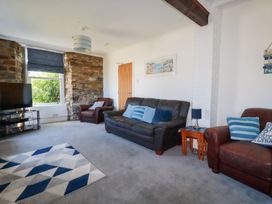 A living room with sofas and a television at Tregundy Farmhouse in Perranporth