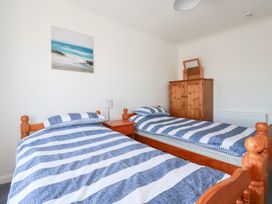 A bedroom with two single beds and a wardrobe at Tregundy Farmhouse Perranporth