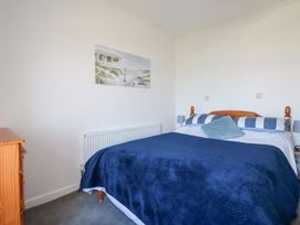 A bedroom with a bed and wall art at Tregundy Farmhouse in Perranporth