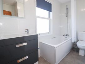 A bathroom with a sink, toilet, and bath at Tregundy Farmhouse in Perranporth