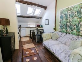 A living room with a sofa and kitchen area at The Little Laura Ashley House in Machynlleth