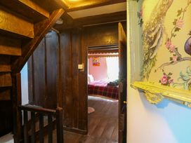 A hallway with a staircase and a doorway leading to a bedroom at The Little Laura Ashley House in Machynlleth