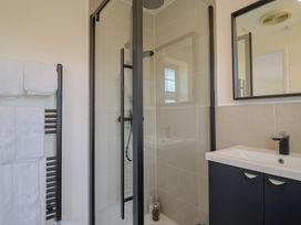 A bathroom with a shower, sink, towels, and mirror at Oakwood in Chideock