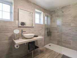 A bathroom with a sink, shower, and mirror at Oakwood in Chideock