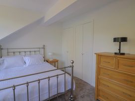 A bedroom with a bed, nightstand, lamp, and dresser at Oakwood in Chideock