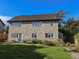 A house with a stone exterior and garden at Oakwood in Chideock