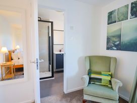 A bedroom with a bed, side table and bathroom entrance at Oakwood in Chideock