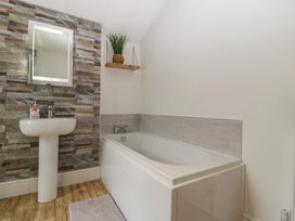 A bathroom with a sink, bathtub and a mirror at Gavin and Stacey House in Barry