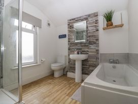 A bathroom with a sink, toilet, shower, and bathtub at Gavin and Stacey House in Barry