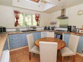 A kitchen with a table and chairs along with appliances at Ty Caredig in Swansea