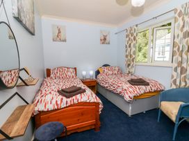A bedroom with two beds and a chair at Ty Caredig Swansea