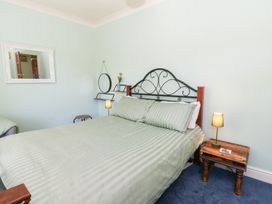 A bedroom with a bed and a mirror at Ty Caredig in Swansea