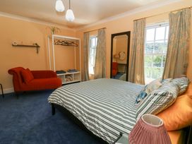 A bedroom with a bed, sofa, and mirror at Ty Caredig in Swansea
