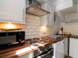 A kitchen with a microwave, cooktop, sink, and dishwasher at Rockside in Salcombe