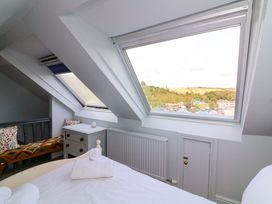 A bedroom with a bed and windows showing a view at Rockside in Salcombe
