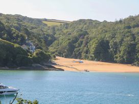 A beach with a house and trees in the background at Rockside in Salcombe