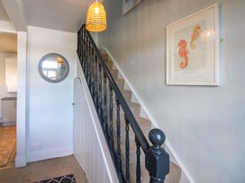 A hallway with a staircase and framed artwork at Rockside in Salcombe