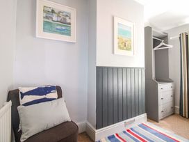 A bedroom with a chair, cushions and storage drawers at Rockside in Salcombe