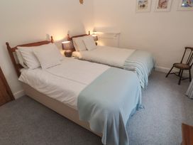 A bedroom with two beds and a chair at 1 Rowes Cottages in Penzance