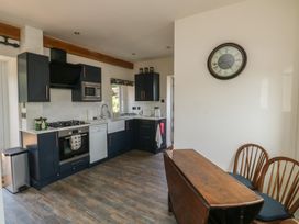 A kitchen with cabinets, stove, sink, and dining area at 13 School Road in Newton Abbot