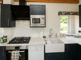 A kitchen with a gas stove, microwave, and sink at 13 School Road in Newton Abbot