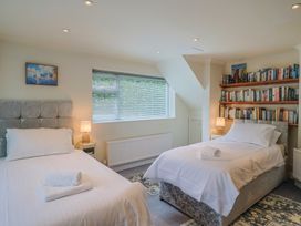 A bedroom with two beds and a bookshelf at Hawksdown in Lyme Regis