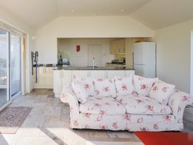 A living room with a sofa facing a kitchen at Hawksdown in Lyme Regis