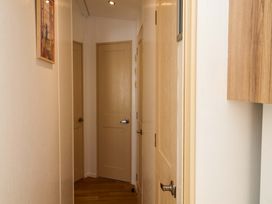 A hallway with multiple doors and artwork at 21 Poplar Avenue, Felixstowe, Suffolk
