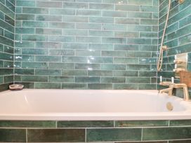 A bathtub with green tiles in a bathroom at Bohemian Beach Cottage in Bournemouth